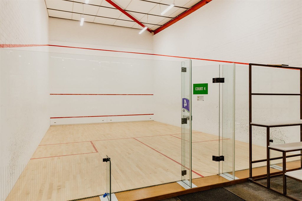 An indoor squash court with glass back wall